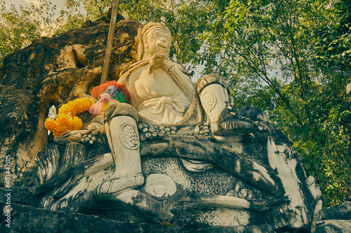 Phayao, Thailand - Nov 29, 2020: Low Angle Marble Sun Wukong or Monkey King Statue on Stone and Baton with Forest Background in Vintage Tone