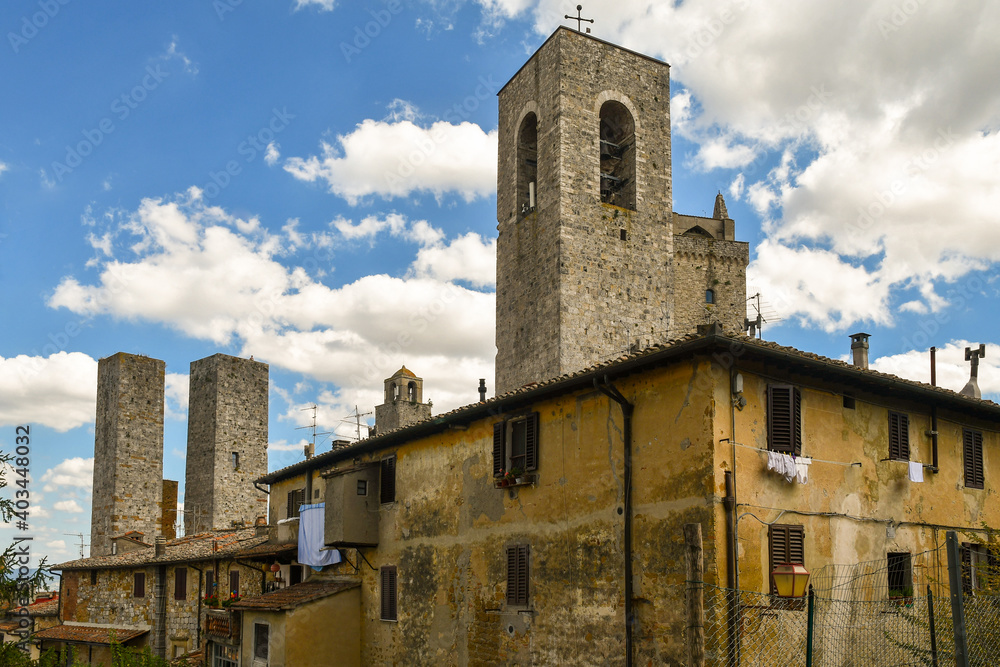 Low-angle view of the historic centre of San Gimignano, Unesco World Heritage Site, with the famous medieval towers against blue cloudy sky, Siena, Tuscany, Italy