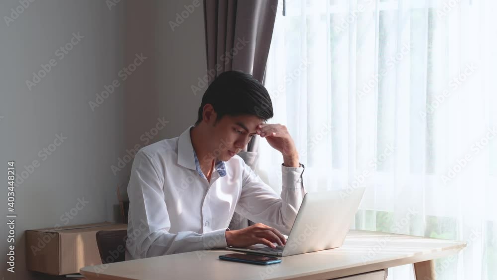 Young busy serious asian man sitting at the table working on laptop, beautiful asian woman bringing him cup of coffee to support and encourage and help to relax during work from home. Young busy serious asian man sitting at the table working on laptop, beautiful asian woman bringing him cup of coffee to support and encourage and help to relax during work from home.