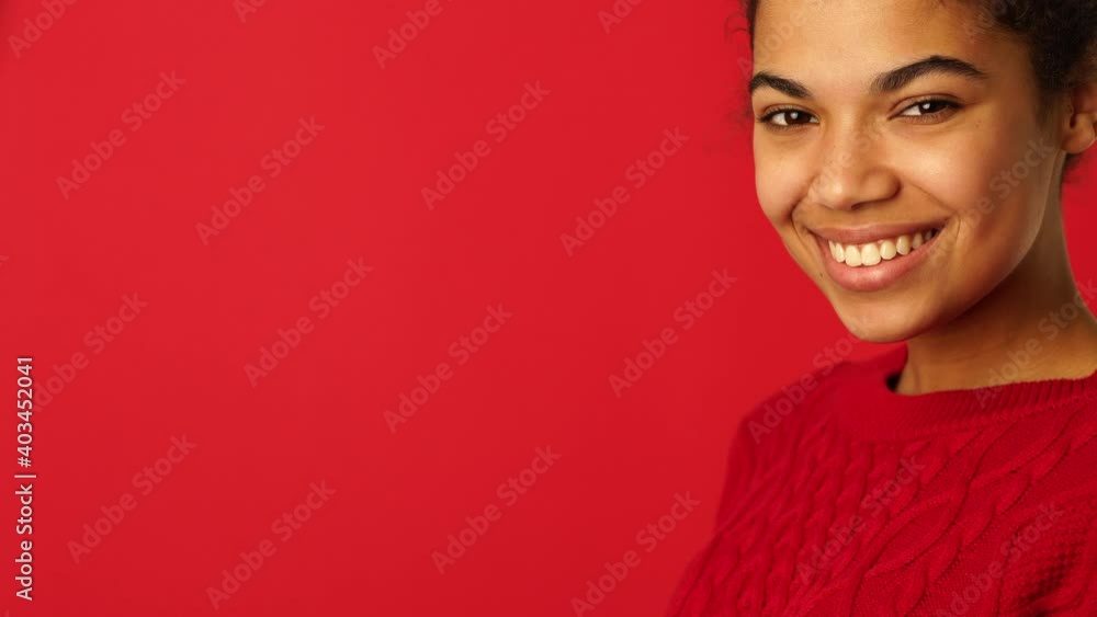 Happiness and Joy. Beautiful mixed race girl turning her head from side to the camera and smiling isolated over red background Happiness and Joy. Beautiful mixed race girl turning her head from side to the camera and smiling isolated over red background