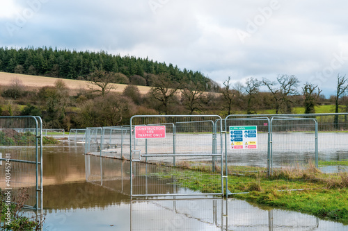 Flood protection works with signs and fences on the overflowed river's banks due to heavy rain on the east England countryside. Selective focus, copy space.