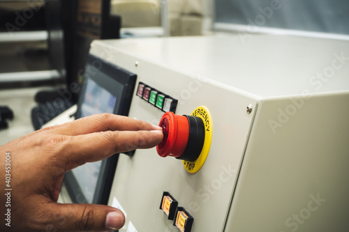 Male Operator use left hand to push emergency button to stop the machine while accidence occur. photo