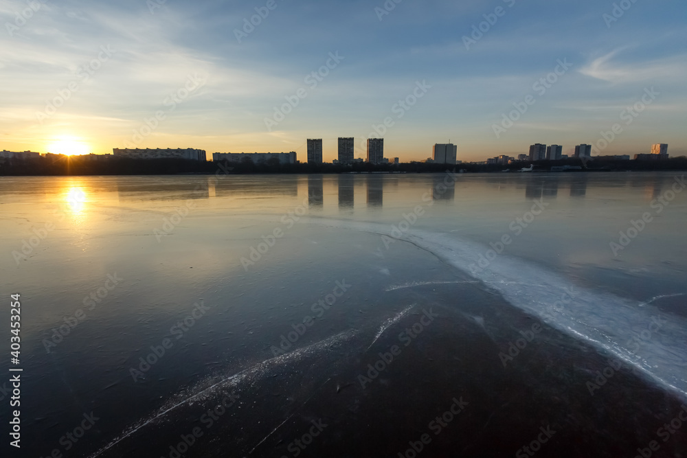 Moscow river in winter at sunset. Reflections of residential buildings on the ice of the Moscow river near the northern river station. Russia, December 2020