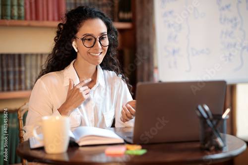 Woman sitting at desk, explaining lesson to students
