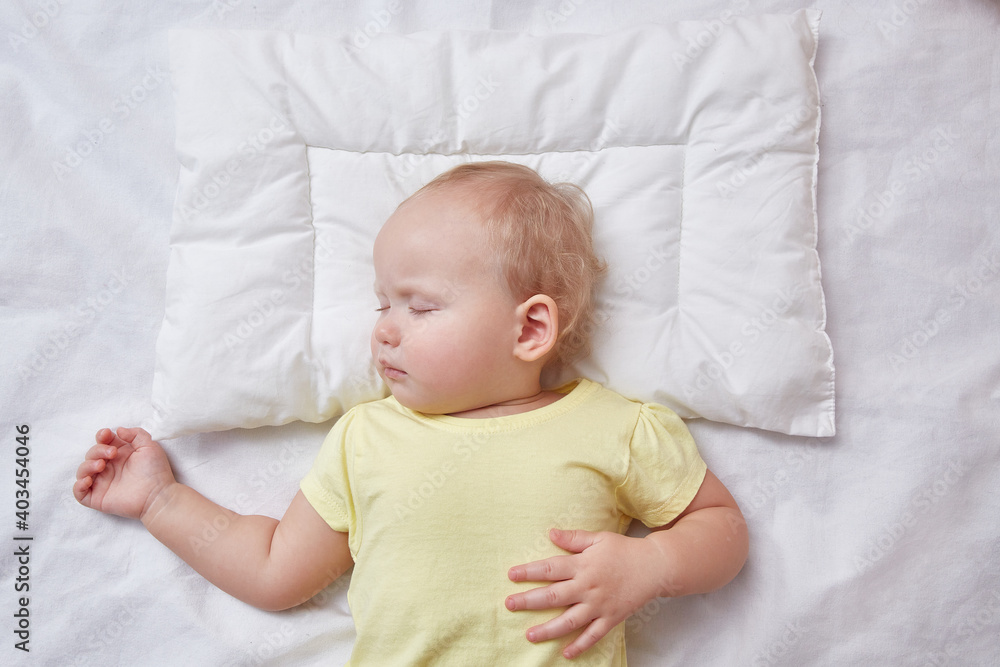 The baby sleeps on a white pillow. The view from the top The baby sleeps on a white pillow. The view from the top