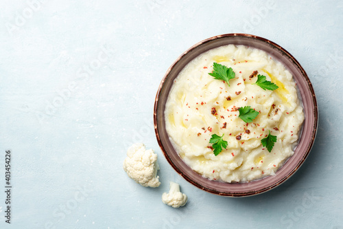 Mashed cauliflower with butter, pink peppercorns and parsley on concrete background photo