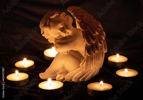 Konstfotografi angel sculpture surrounded by burning candles; grief and loss memory of the deat