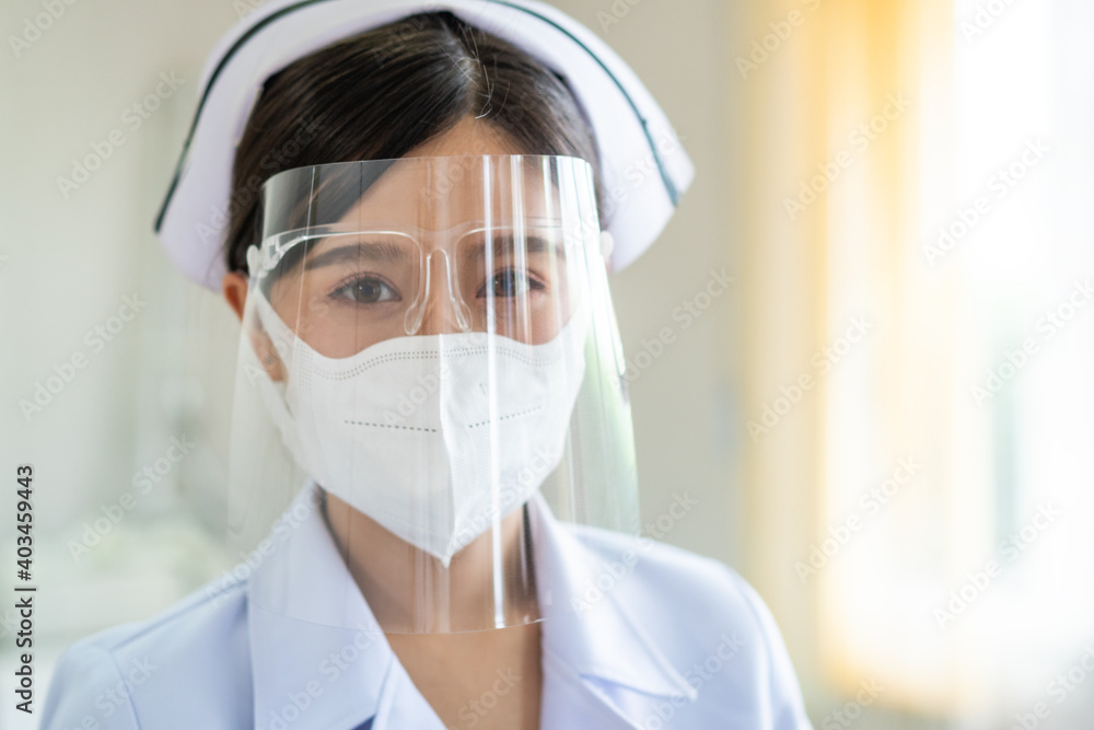 Portrait of Thai female nurse wearing protective mask and face shield in hospital. Young Asian medical staff in white uniform looking at camera. Healthcare concept. copy space Portrait of Thai female nurse wearing protective mask and face shield in hospital. Young Asian medical staff in white uniform looking at camera. Healthcare concept. copy space