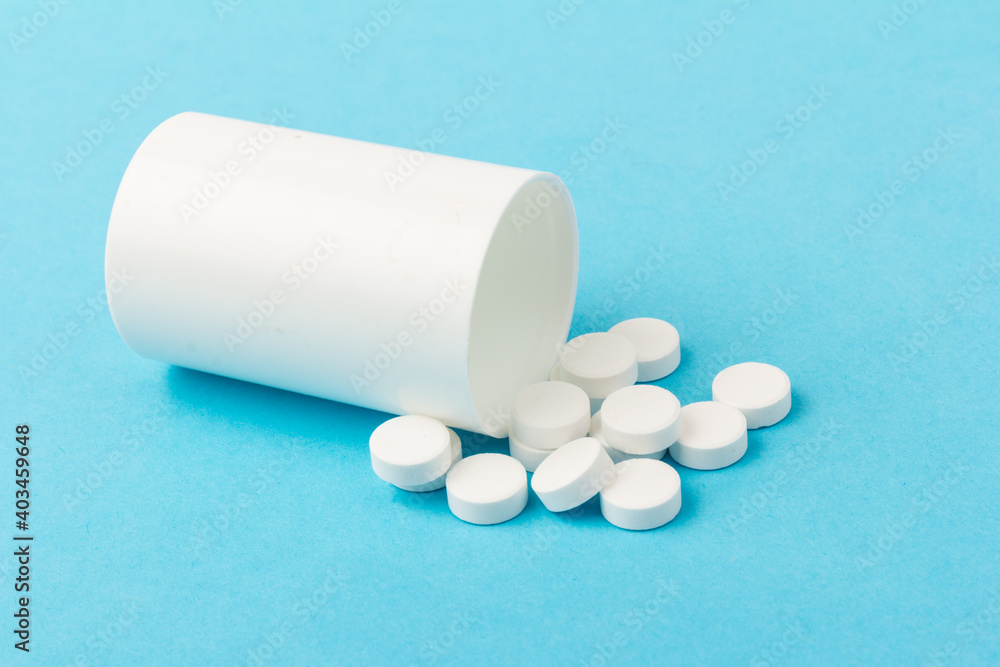 White tablets and bottle for tablets on blue background