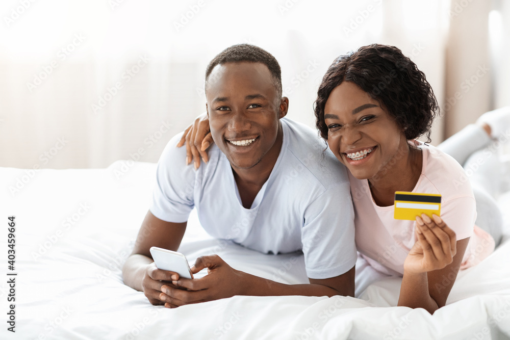 Positive african man and woman with credit card and smartphone