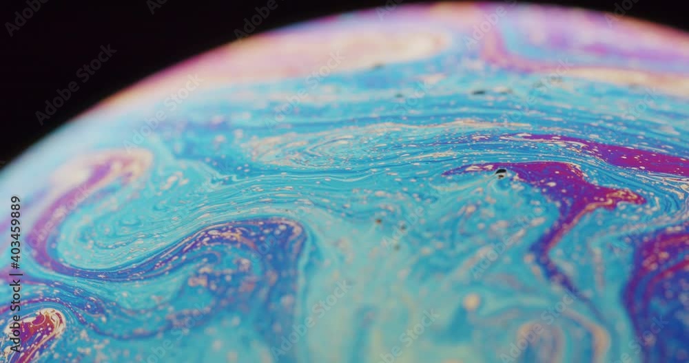 Extreme close up of a beautiful rainbow colored sphere. Small particles flowing in the jet stream of the sphere. Experimental art shot of a science experiment, shallow depth of field, black background Extreme close up of a beautiful rainbow colored sphere. Small particles flowing in the jet stream of the sphere. Experimental art shot of a science experiment, shallow depth of field, black background