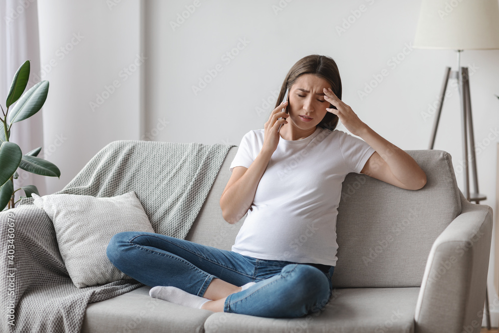 Pregnant Woman Feeling Unwell While Talking On Cellphone At Home, Having Headache Pregnant Woman Feeling Unwell While Talking On Cellphone At Home, Having Headache