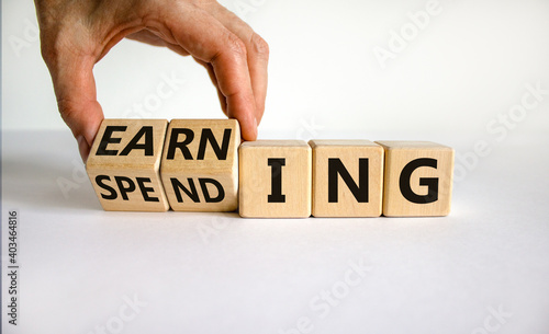 Earning or spending symbol. Businessman hand turns cubes and changes the word 'spending' to 'earning'. Beautiful white background, copy space. Business and earning or spending concept.