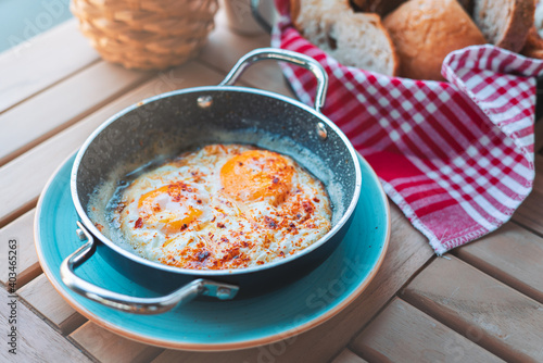 Fried Eggs dressed. Breakfast sunny side up eggs with seasoning on copper pan photo