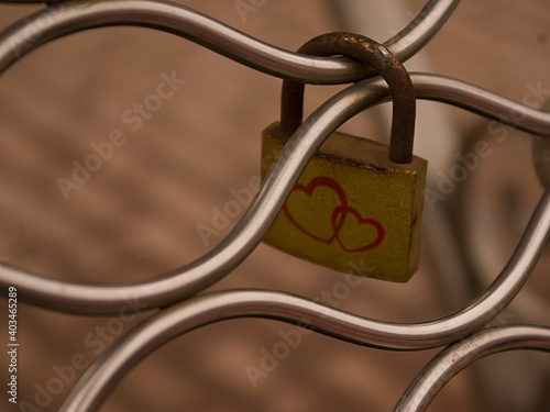 Closed padlock with a painted heart for a couple in love on iron bars