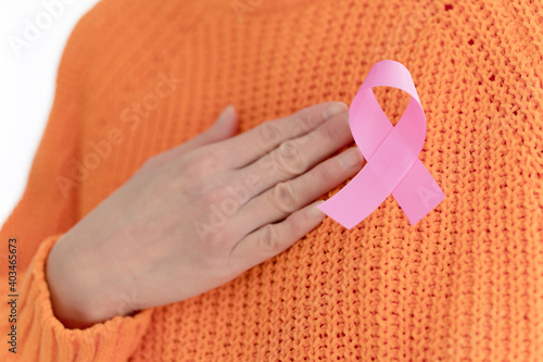 close up of woman in knitted sweater with pink breast cancer awareness ribbon photo