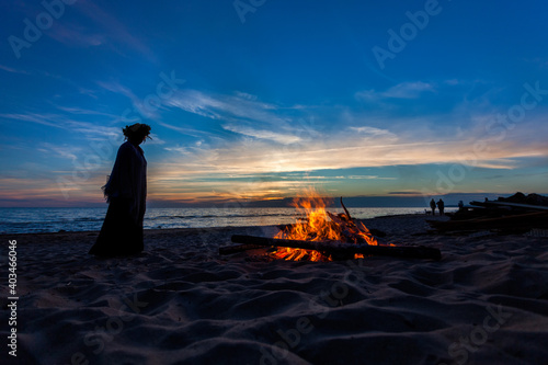 Fototapeta Naklejka Na Ścianę i Meble -  Unrecognisable people celebrating summer solstice with large bonfires on Baltic Sea sandy beach