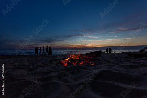 Fototapeta Naklejka Na Ścianę i Meble -  Unrecognisable people celebrating summer solstice with large bonfires on Baltic Sea sandy beach