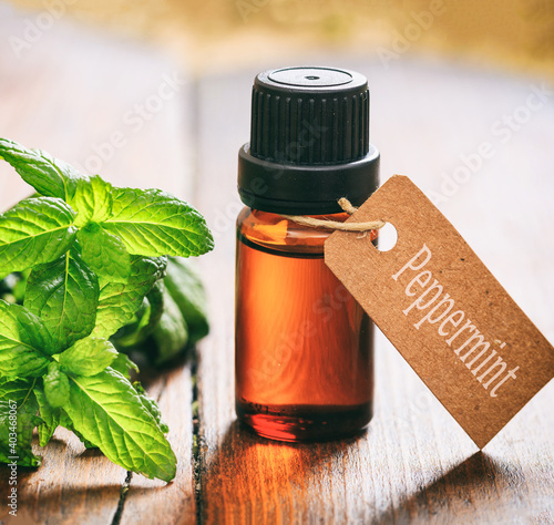 Fototapeta Naklejka Na Ścianę i Meble -  Peppermint essential oil, fresh leaves and blossoms on wooden background