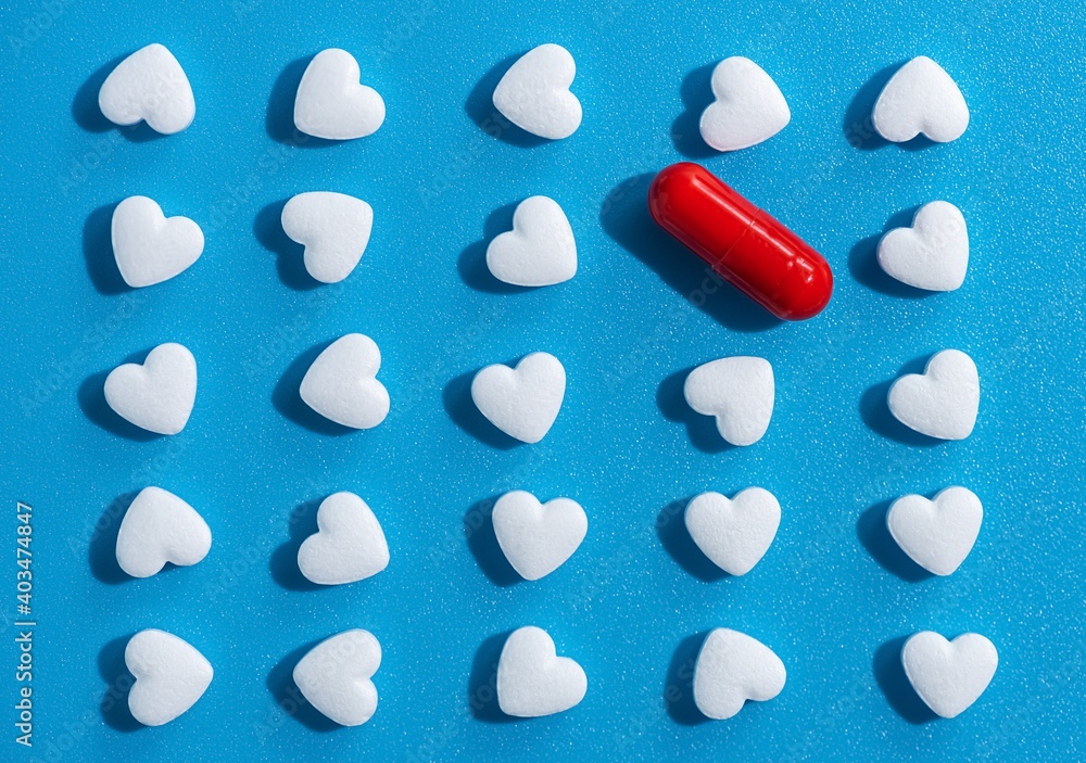 heart-shaped tablets and red pill. pattern on blue background. medicine, cardiology, health. top view, flat lay heart-shaped tablets and red pill. pattern on blue background. medicine, cardiology, health. top view, flat lay