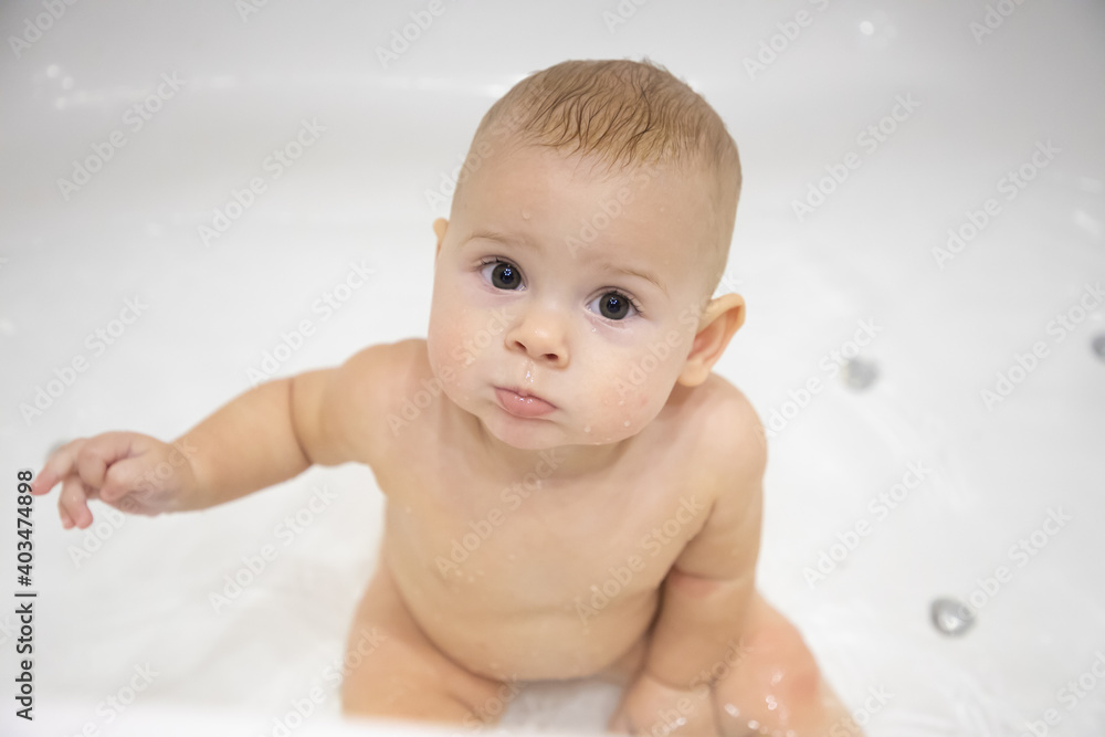 Cute baby girl bathing with toys and smiling in a big white bath Cute baby girl bathing with toys and smiling in a big white bath