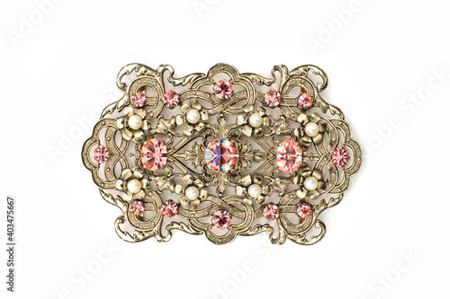 Gold brooch with pink stones on a white background. Large brooch