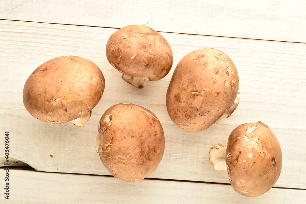 Several organic fresh, cream mushrooms, close up, on a wooden table. Several organic fresh, cream mushrooms, close up, on a wooden table.