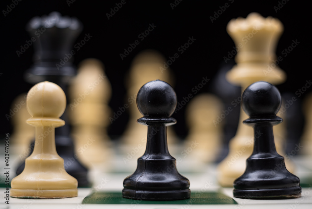 Extreme close up of chess pieces arranged on a portable chessboard before a black background. Extreme close up of chess pieces arranged on a portable chessboard before a black background.