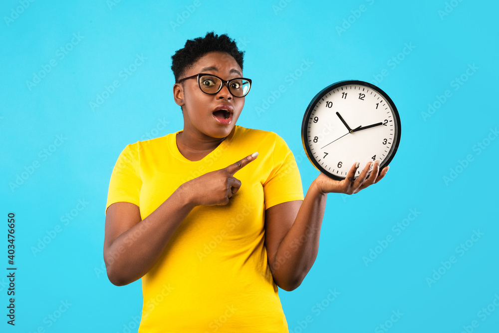 Oversized African Woman Showing Clock Posing Standing Over Blue Background Oversized African Woman Showing Clock Posing Standing Over Blue Background