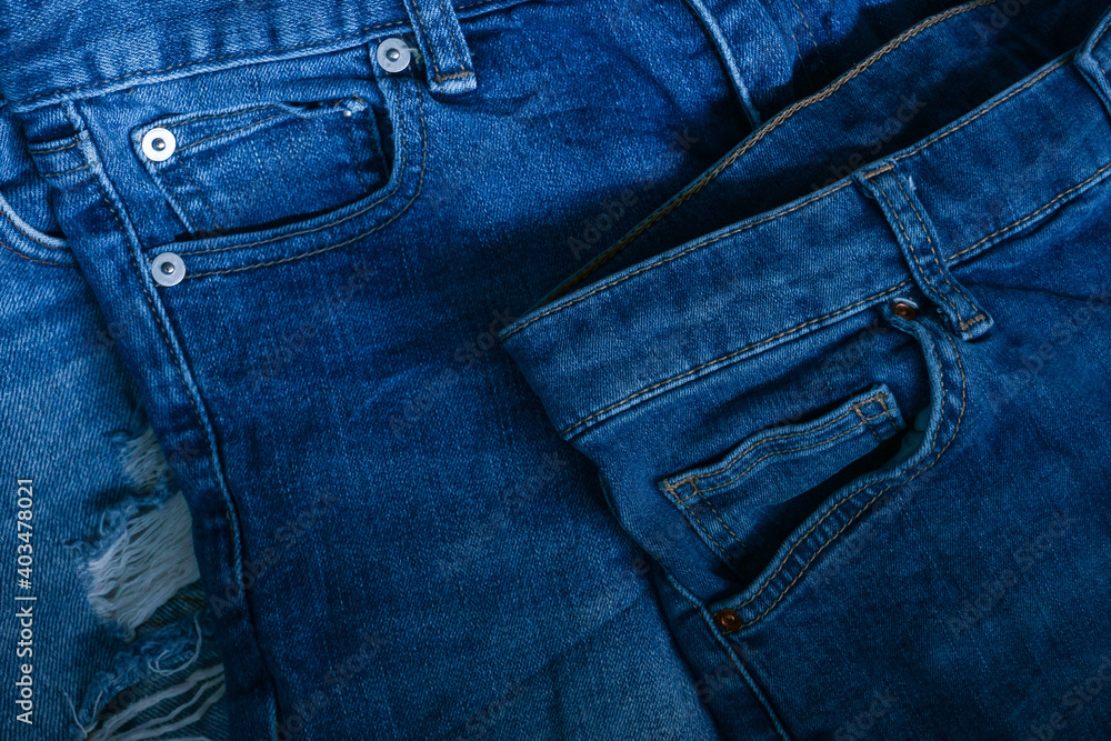 Blue jeans pants clothes pile background. Stack of blue jeans on shop desk,Denim jeans background. Destroyed torn classic denim blue jeans patches, banner fashion background Blue jeans pants clothes pile background. Stack of blue jeans on shop desk,Denim jeans background. Destroyed torn classic denim blue jeans patches, banner fashion background
