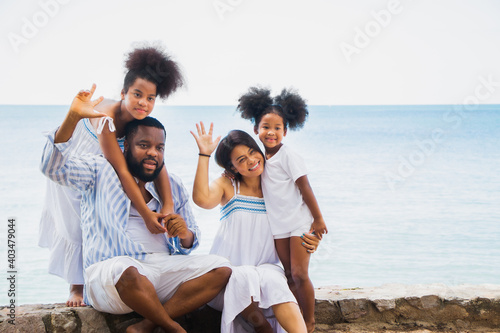 Happy African American family, father, mother and daughters happiness vacation relax with sea background
