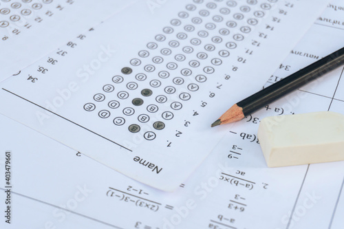 Pencil and eraser on answer sheets or Standardized test form with answers bubbled. multiple choice answer sheet