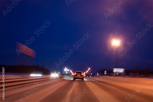 Night highway in winter. Light headlights in the dark, the movement of cars from the viewer