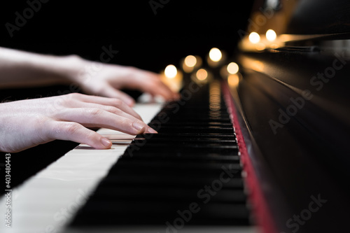 Hands playing the piano keyboard closeup and candle light bokeh background. Male pianist learning to play the piano instrument and beautiful music