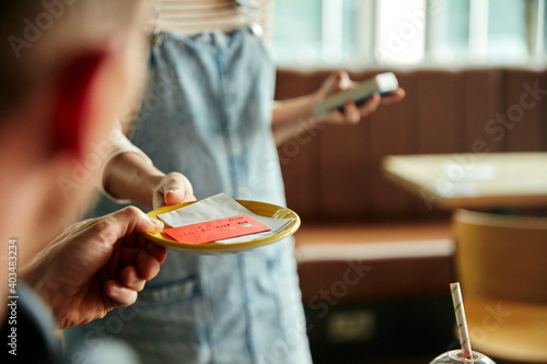 Woman holding contactless payment terminal for a customer paying by card photo