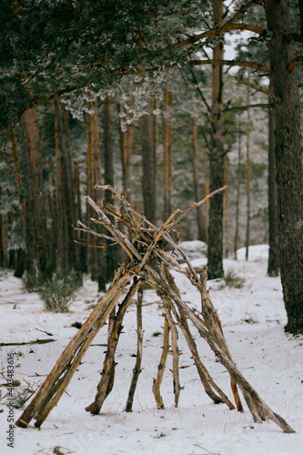 Cabaña con palos en bosque nevado 