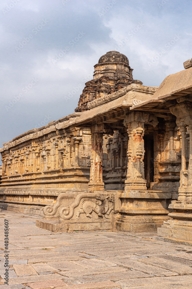 Hampi, Karnataka, India - November 5, 2013: Sri Krishna temple in ruins. Massive yellow-brown facade with steps to enter, sculpted pillars, and dome vimanam under light blue cloudscape. Hampi, Karnataka, India - November 5, 2013: Sri Krishna temple in ruins. Massive yellow-brown facade with steps to enter, sculpted pillars, and dome vimanam under light blue cloudscape.