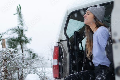chica joven sentada en la parte trasera de un 4x4 con ropa de invierno mientras esta nevando en la montaña © aritz