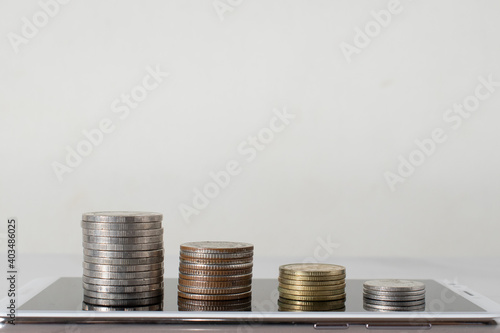 stack of coins on smart phone on white background. Business and money saving and technology concept. Online shopping