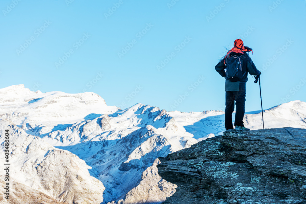 A mountaineer contemplating the landscape of the Sierra Nevada mountains with snow.