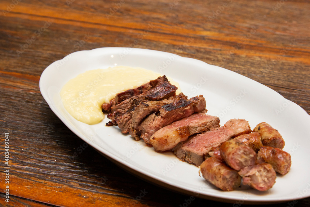 Barbecue with anchovy meat and sausage served with aligot. Barbecue with anchovy meat and sausage served with aligot.