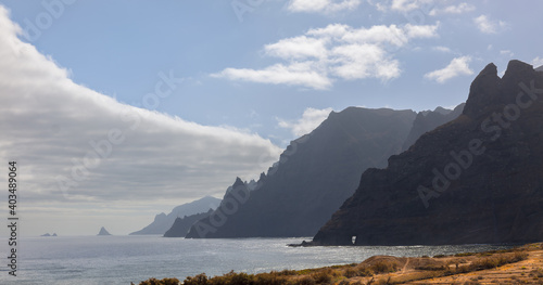 The wild coast with high cliffs and sharp rocks in the Atlantic on the eastern north side of Tenerife. It's a hazy morning with a lot of water in the air.