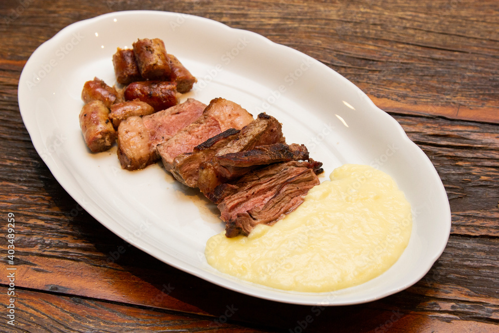 Barbecue with anchovy meat and sausage served with aligot. Barbecue with anchovy meat and sausage served with aligot.