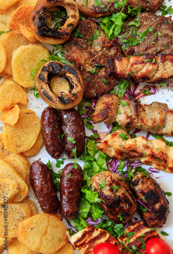 Vertical closeup top view of mixed grilled meat with vegetables and potatoes. photo