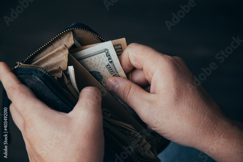 An empty wallet with a small amount of money in the hands of a working man. Poverty concept
