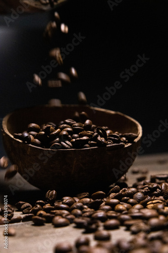 coffee beans in coconut bowl on a dark wooden background