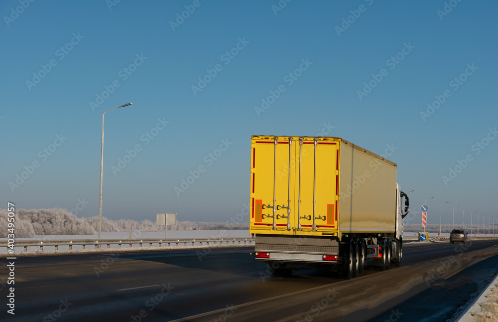 Truck driving on the asphalt road in winter rural landscape