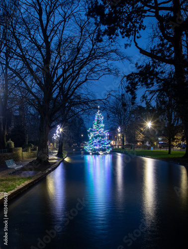 Long exposure image of the the Christmas tree at Bourton-on-the-Water in The Cotswolds reflecting in the river.