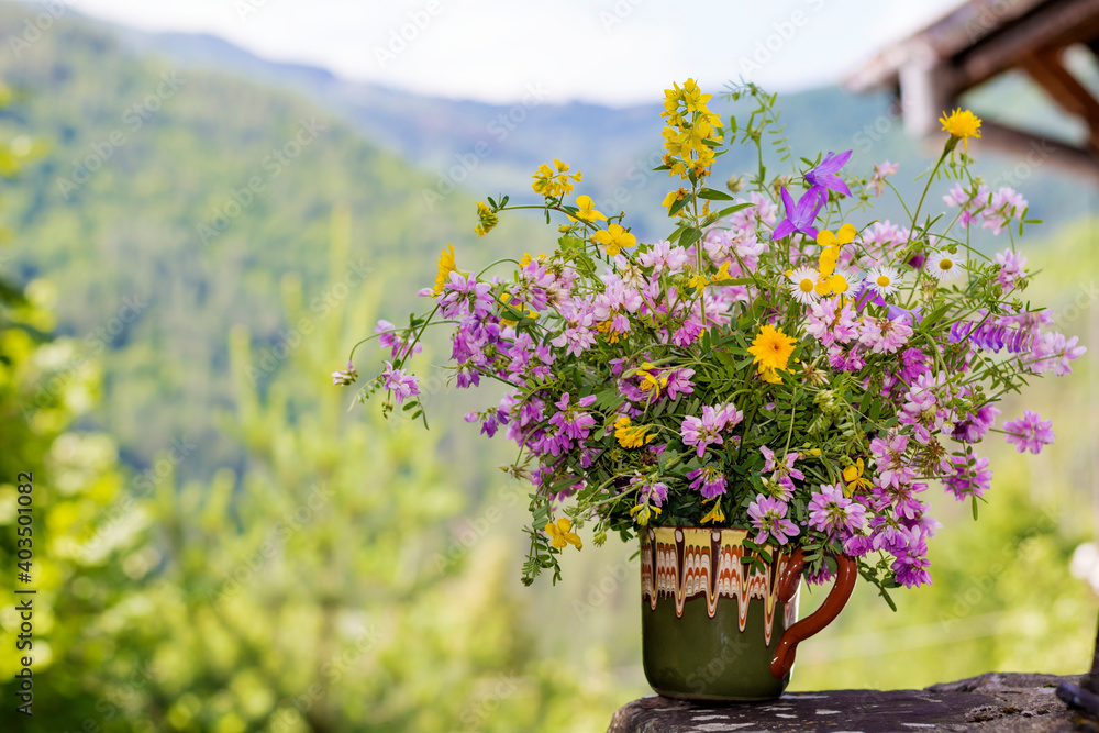 Beautiful Wild Spring Purple and Yellow Flowers  in a Small  Vintage Vase on a Summer Mountain Hills Background 