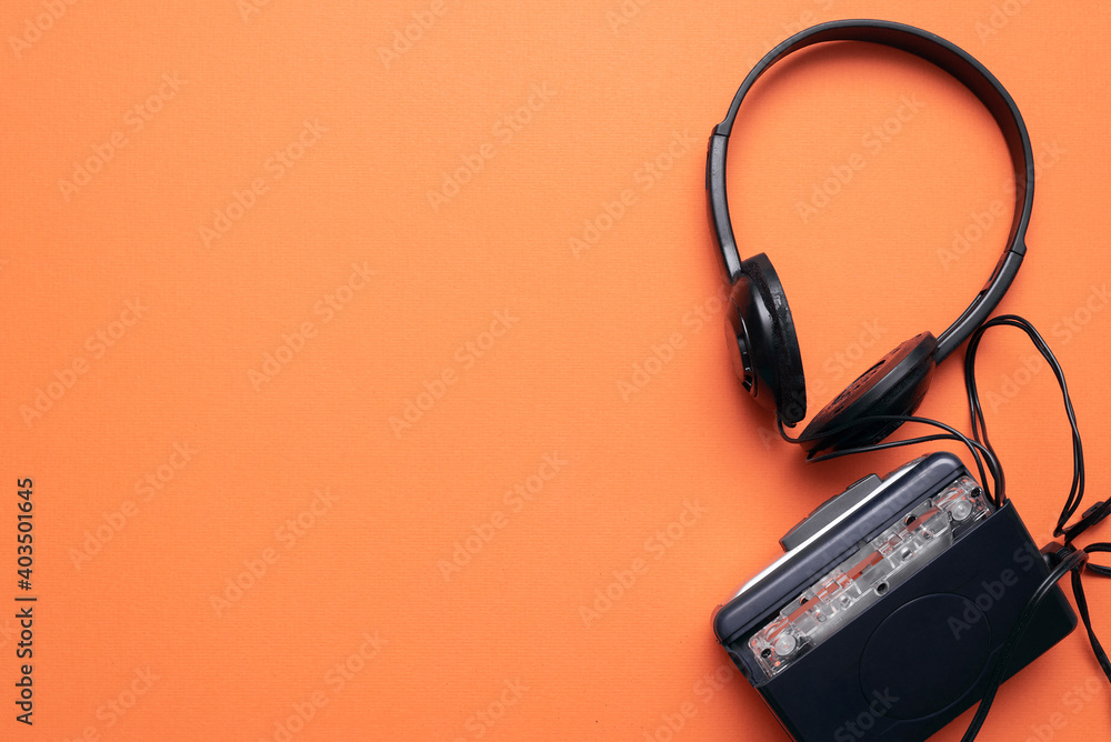 Old retro stereo cassette player and headphones on the orange flat lay background. Old retro stereo cassette player and headphones on the orange flat lay background.